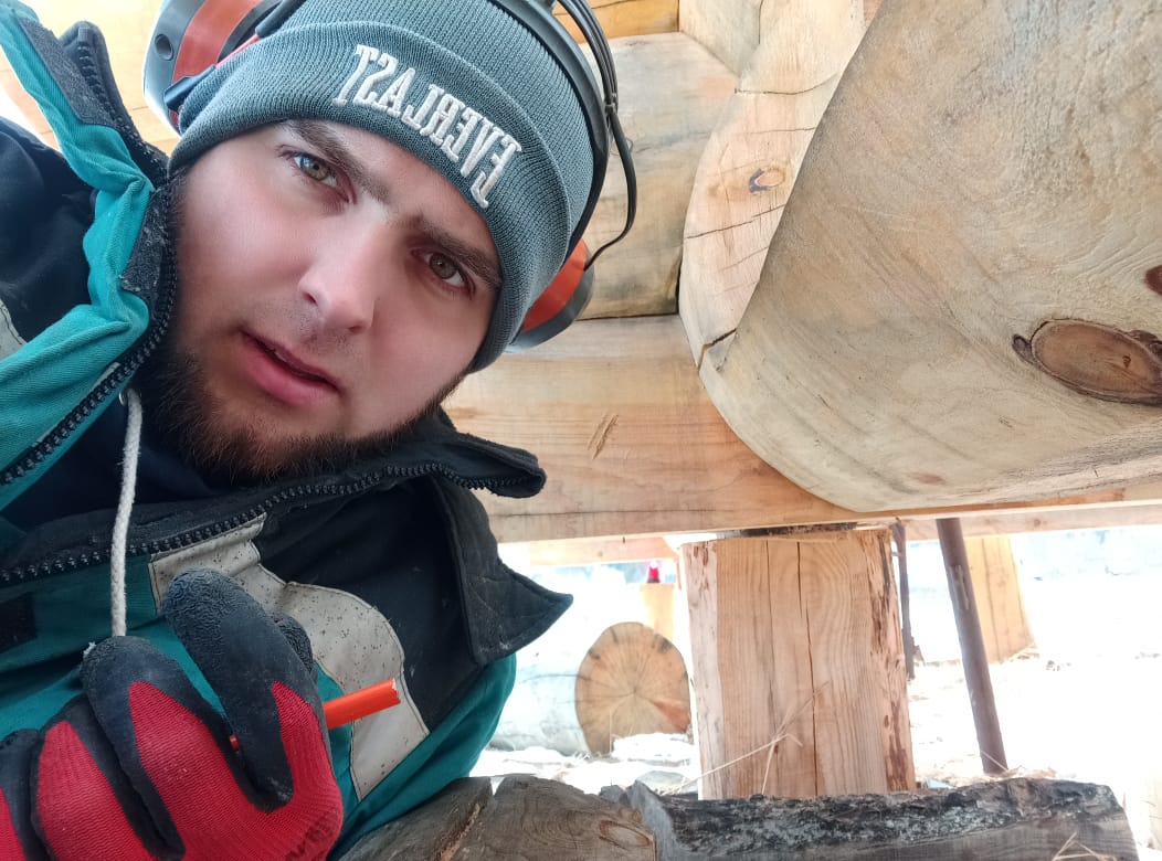 Master craftsman Ilia Zubko working with hand-scribed timber in Siberian winter conditions