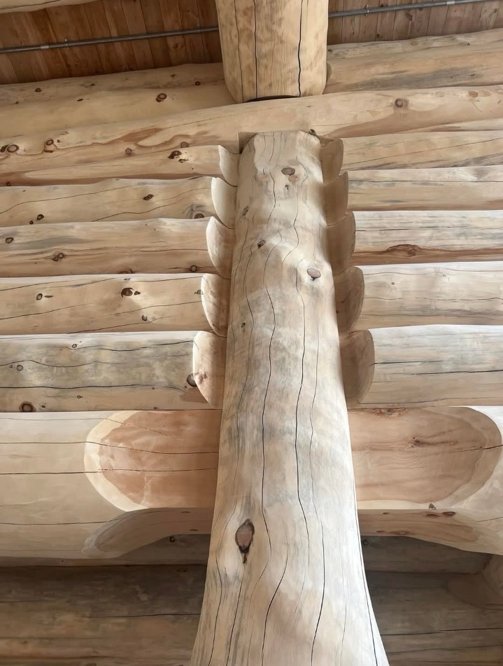 Hand-scribed column joint where timber meets wall